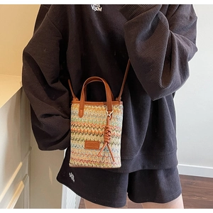 Detail of colorful woven straw mini crossbody bag with brown leather handles and strap