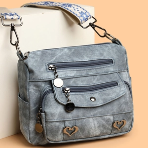 Blue denim multi-pocket crossbody bag with heart charm and geometric jacquard strap