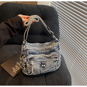 Détail d'un sac bandoulière en jean vintage avec plusieurs zips et bandoulière tissée