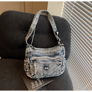Détail d'un sac bandoulière en denim bleu vintage avec fermetures éclair et sangle large