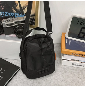 Detail view of the black nylon drawstring bottle bag with adjustable shoulder strap