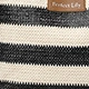Macro detail of black and white striped woven tote bag with a brown leather label