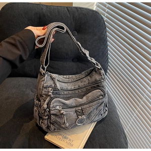 Détail du sac bandoulière en denim gris délavé avec poches zippées et sangle réglable