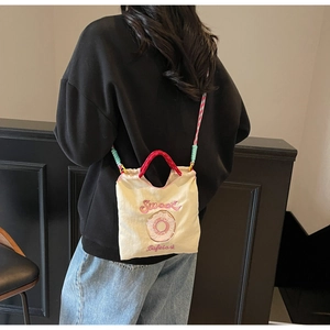 Détail du sac bandoulière en toile beige avec broderie et bandoulière tissée colorée