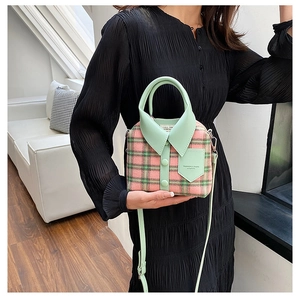 Detailed view of creative shirt-style crossbody bag with green plaid and button detail