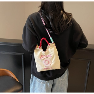 Détail du sac à main en toile brodé avec bandoulière tissée et motif de donut rose