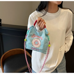 Détail du sac en toile bleu doux avec poignées roses et broderie de donut chic
