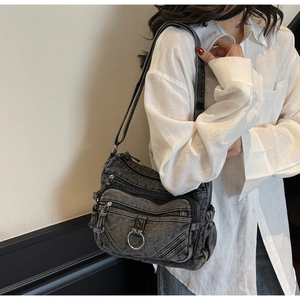 Détail du sac à bandoulière en denim noir avec compartiments à fermeture éclair