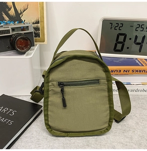 Detail of army green nylon crossbody water bottle bag with zipper pocket and strap
