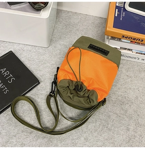 Close-up of lightweight nylon crossbody bag in orange and olive with drawstring top