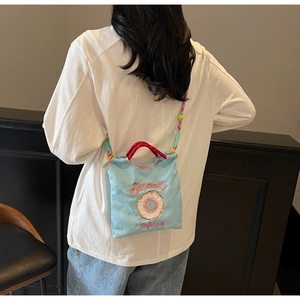 Détail du sac bandoulière en toile bleu clair avec broderie donut Sweet et sangle tissée