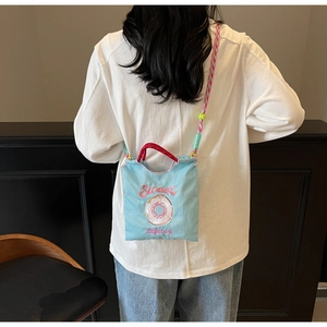 Gros plan du sac bandoulière en toile bleu clair avec broderie et sangle tissée