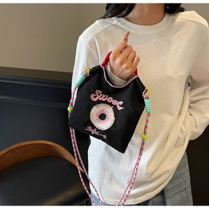 Détail du sac en nylon noir avec broderie de donut et bandoulière tissée colorée