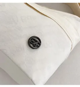 Detailed close-up of the black circular logo on the cream-colored nylon crossbody bag