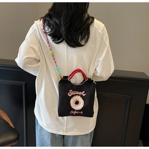 Détail d'un petit sac bandoulière en toile noire avec broderie et sangle colorée