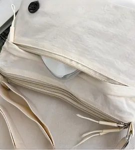 Detail of multi-pocket crossbody bag in off-white nylon with secure zipper storage
