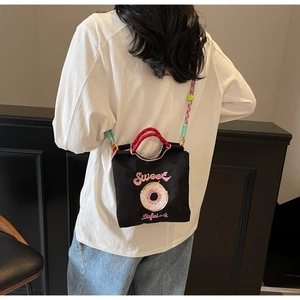Détail de la broderie donut rose et du lettrage Sweet sur un sac en toile noire