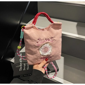 Détail du sac en nylon rose avec broderie sweet et bandoulières tissées colorées