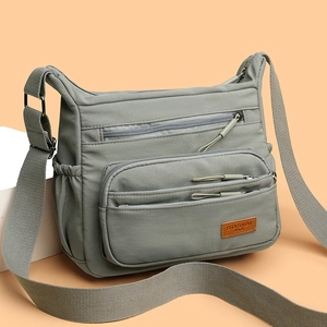 Minimalist grey nylon crossbody bag with multi-zipper pockets and wide shoulder strap
