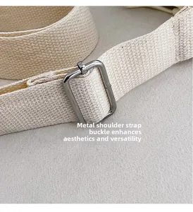 Close-up of adjustable metal buckle on beige canvas shoulder strap for crossbody bags