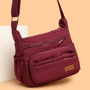 Waterproof burgundy nylon crossbody bag with multiple pockets and adjustable strap