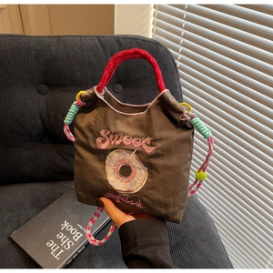 Détail macro du sac à cordon marron avec broderie colorée et poignée en corde tressée