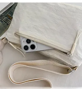 Close-up of the rear zipper pocket of the nylon crossbody bag holding a smartphone