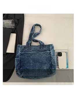 Detail shot of a blue washed denim tote bag with side pockets and stitched compartments