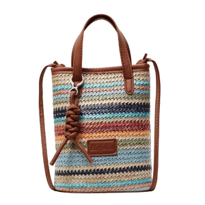 Vertical striped straw crossbody bag with colorful woven patterns and brown leather straps