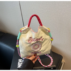 Détail du sac en toile avec broderie Sweet, motif donut et poignée tressée rouge