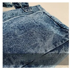 Macro shot of blue washed denim tote fabric showing texture and reinforced stitching