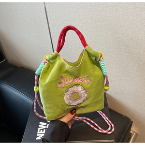 Détails de broderie sur sac en toile verte avec poignées roses et cordons de serrage colorés