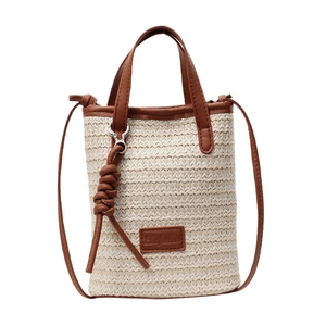 Woven straw crossbody bag with brown leather trim and handles for summer beach