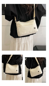 Detailed view of off-white wrinkled nylon crossbody bag with metallic logo and adjustable strap