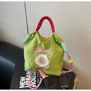 Détail du sac en tissu vert avec broderie Sweet rose et bandoulières tressées colorées