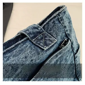 Macro shot of reinforced X-shaped stitching on dark blue denim tote bag shoulder strap