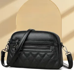 Detailed view of black litchi grain leather bag with quilted pattern and metal hardware