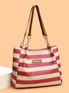 Detail of red and white striped straw tote bag featuring brown leather logo and chain strap