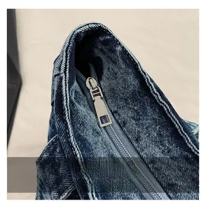 Close-up of smooth metal zipper detail on high-quality dark blue denim tote bag