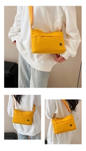Detail of bright yellow crossbody bag with adjustable strap and zip pockets