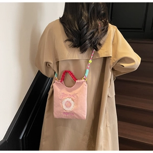 Détail de la broderie Sweet Donut Bakehouse sur un sac en toile rose avec sangle en perles