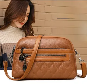 Detail of warm brown lychee leather crossbody bag with quilted rhombic pattern and zippers