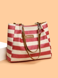 Detail of red and white striped straw tote bag featuring a leather logo patch and chain straps