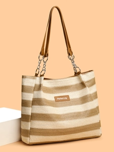Detail of woven straw tote bag featuring brown stripes and metal chain strap accents