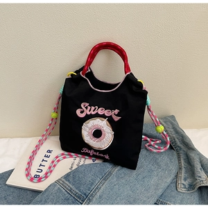 Détail du sac à main en toile brodée avec bandoulière tissée colorée et motif donut