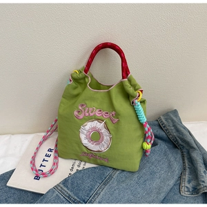 Détail du sac à main brodé vert avec motif de donut et poignée tissée colorée