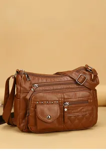 Détails d'un sac bandoulière en cuir marron avec zips et ornements de rivets