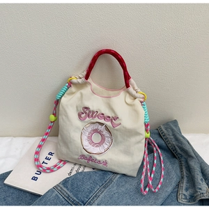 Détail du sac en toile avec broderie de donut et anses en corde tressée colorée