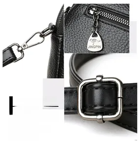 Macro detail of black lychee leather bag featuring dark metal zippers and adjustable buckle