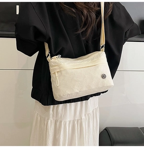 Detail of off-white waterproof nylon crossbody bag with adjustable strap on a model